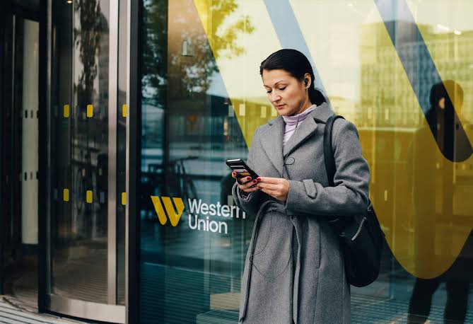 Customer checking her transfer on a phone outside a Western Union branch